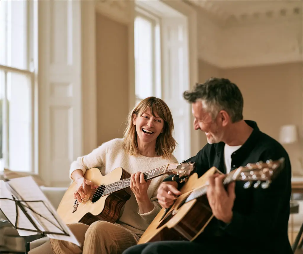 Woman and man laughing as they play acoustic guitars together in a bright room.