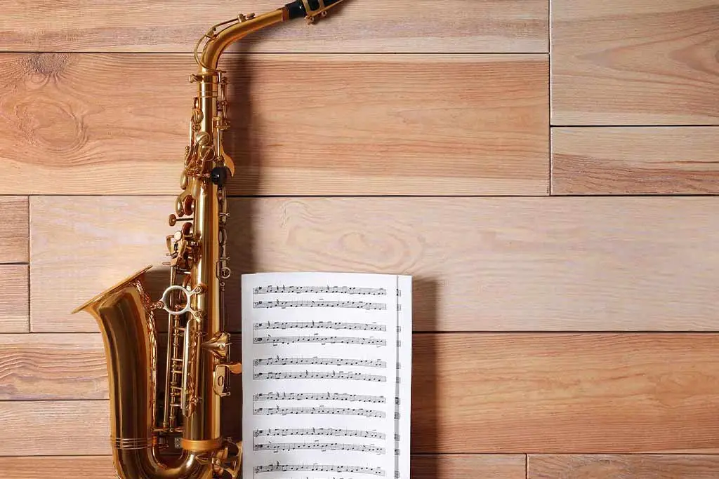 Alto saxophone beside open sheet music on wooden floor