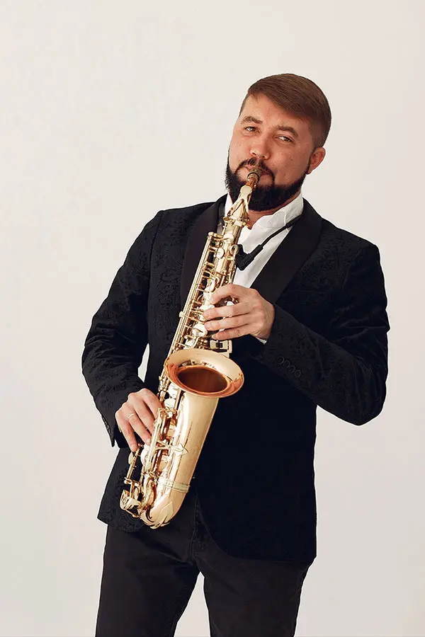 Bearded man in a suit playing a saxophone