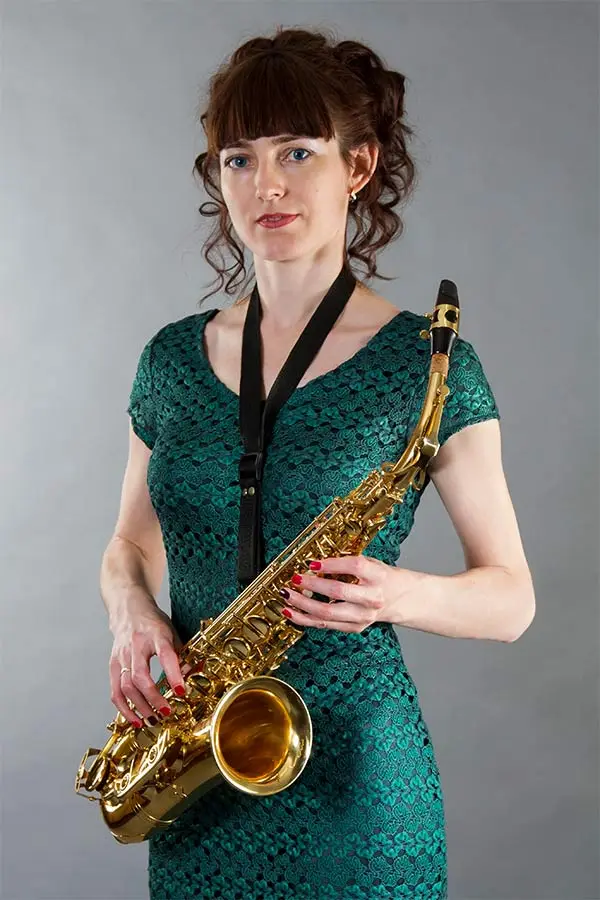Beautiful woman in green dress holding saxophone