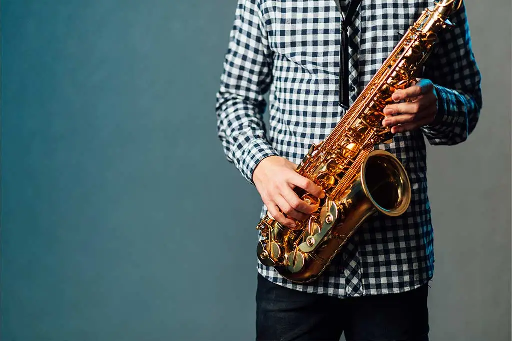 Man in a checked shirt holding a saxophone