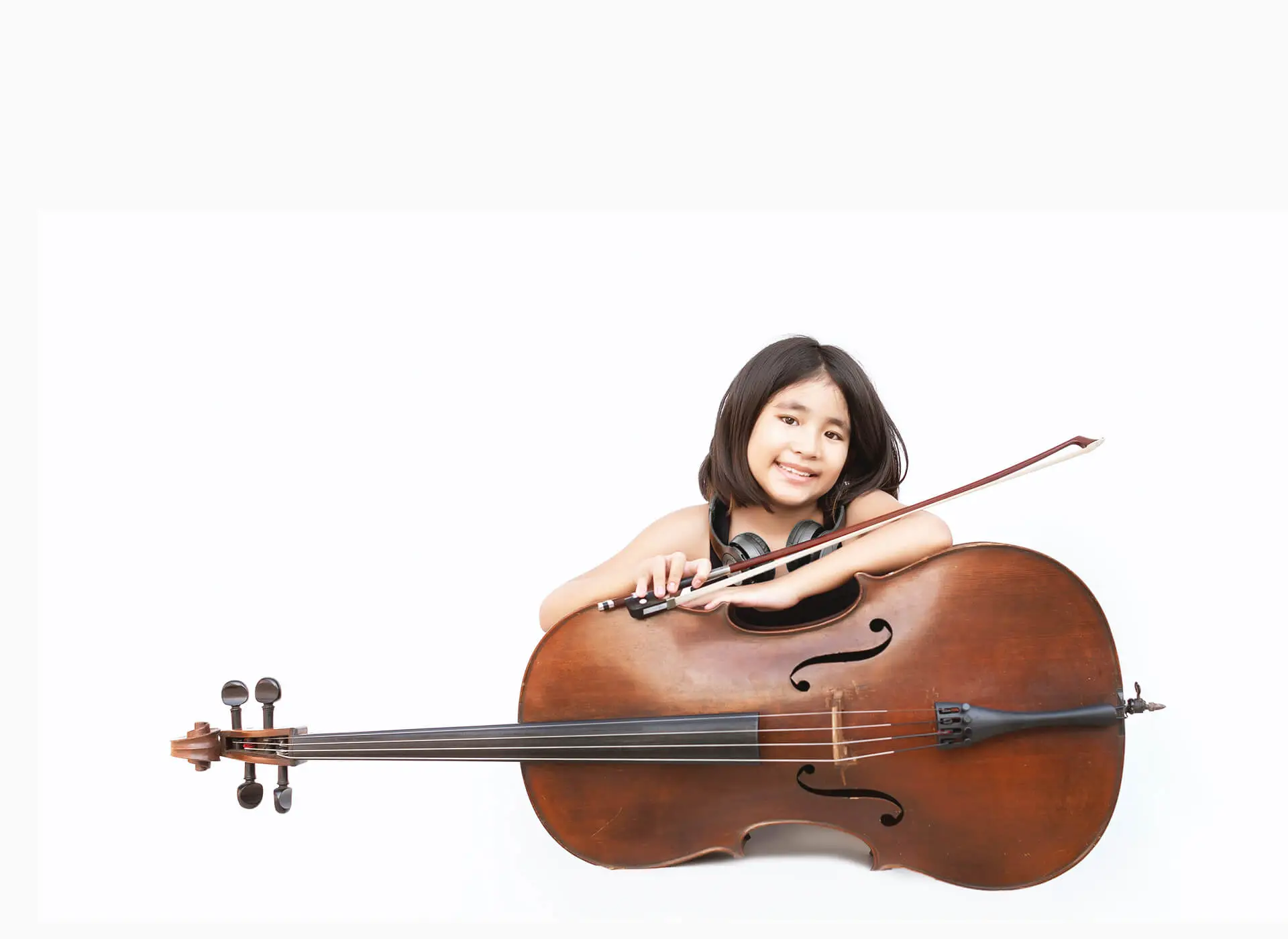 Child holding a cello with headphones around her neck