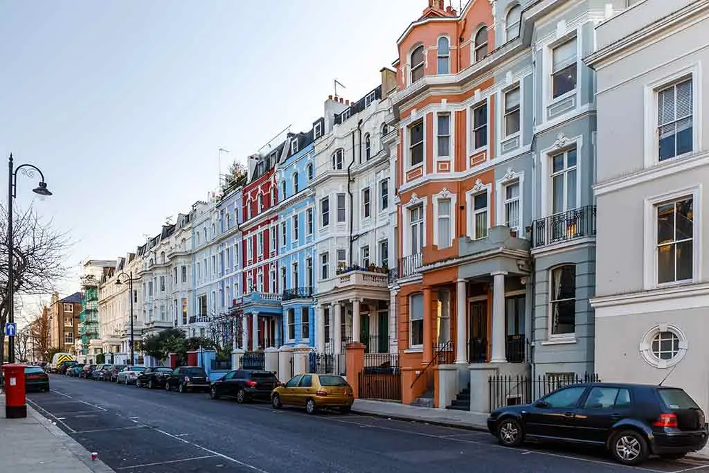 Colourful terraced houses lining a quiet street with parked cars