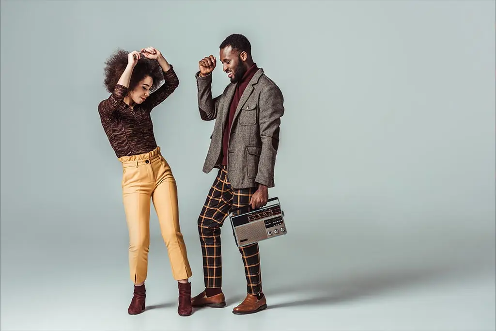 Smiling couple dancing in retro outfits with a boombox
