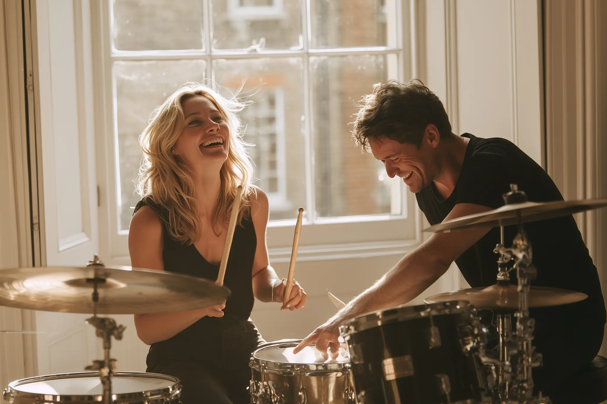 Drum teacher pointing at the snare as a student laughs behind the kit.