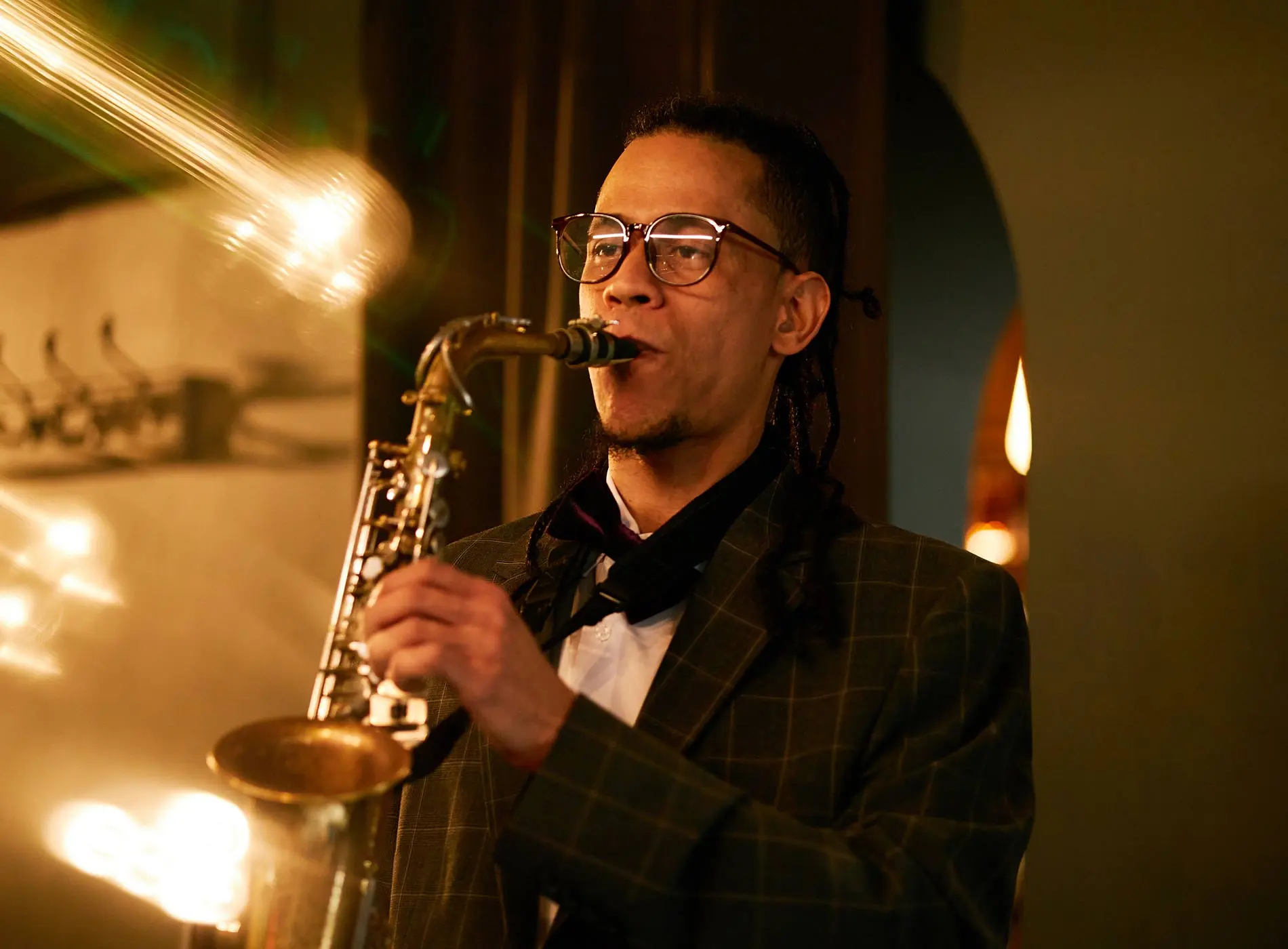 Man with glass and suit playing saxophone