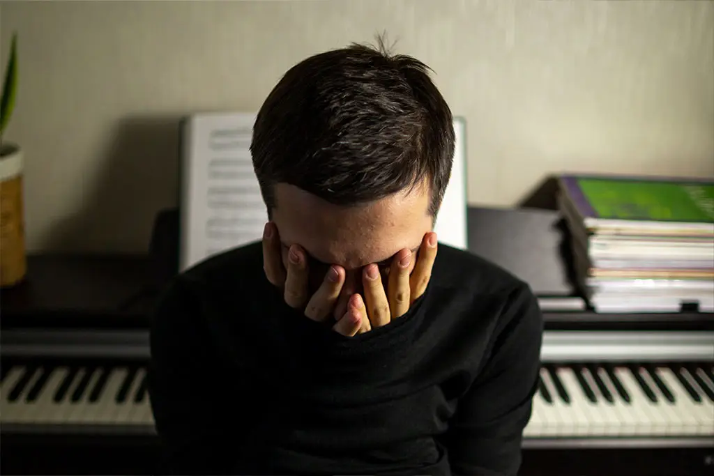 Frustrated adult man with piano on the back