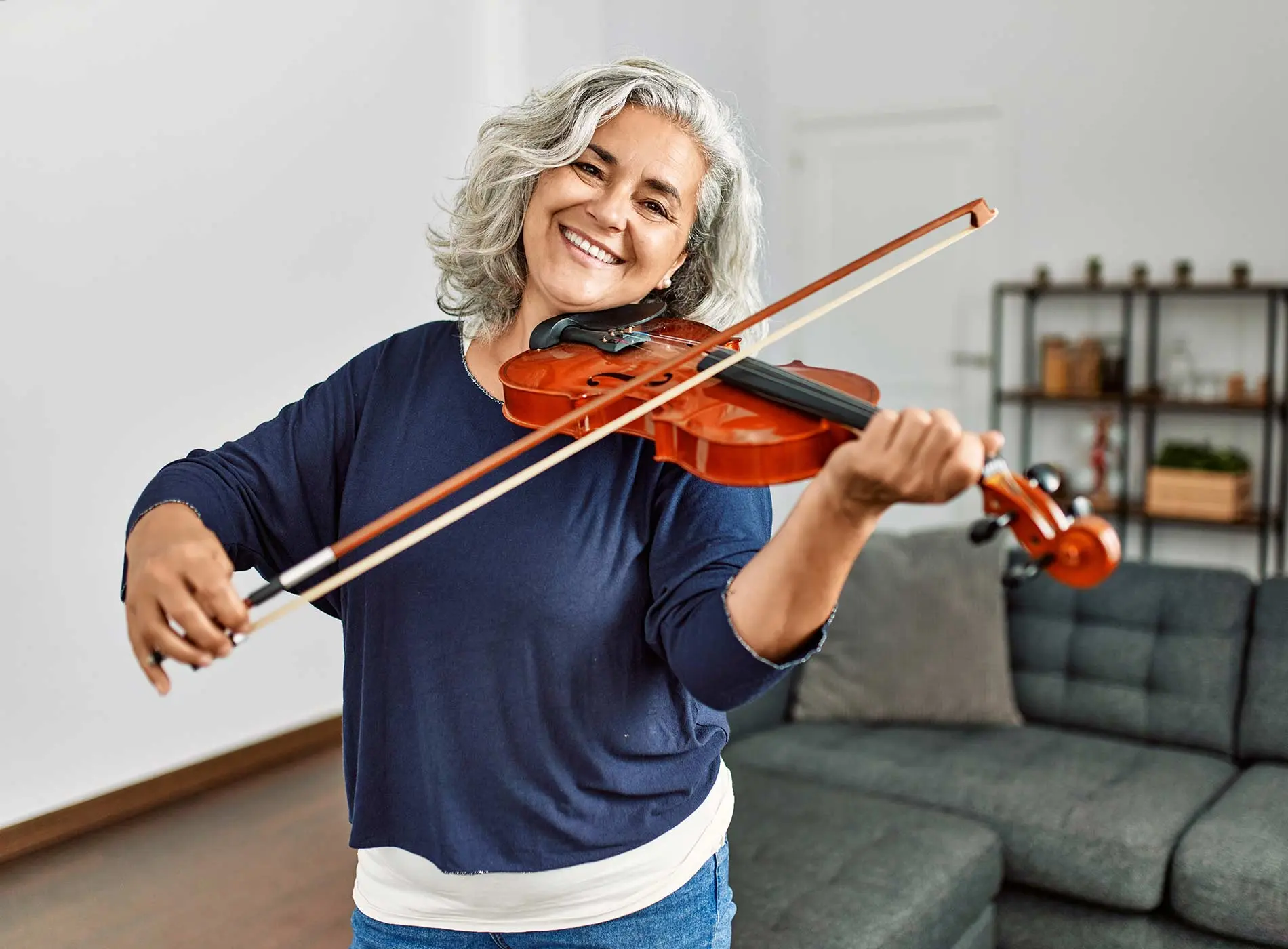 Gray haired middle aged woman happily playing the violin