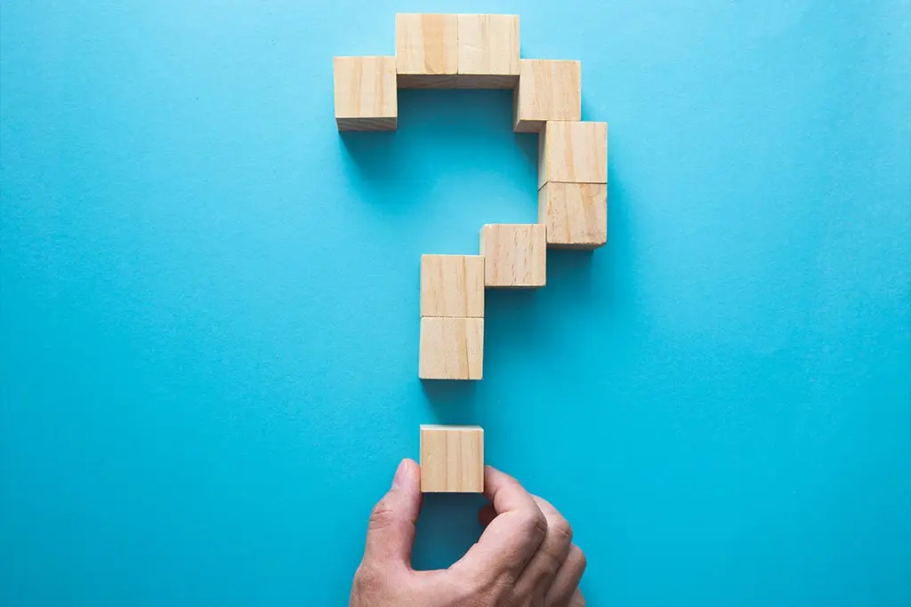 Hand arranging wooden blocks into a question mark