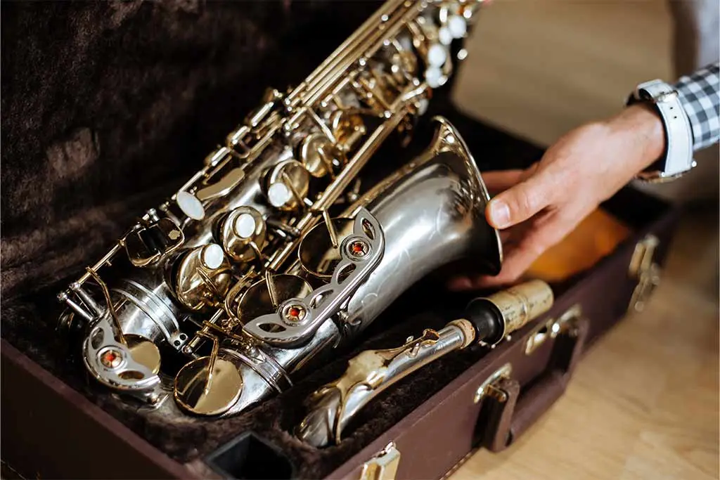 A hand holding a saxophone in an open case