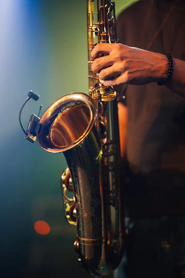 Hand holding a saxophone on a dim stage