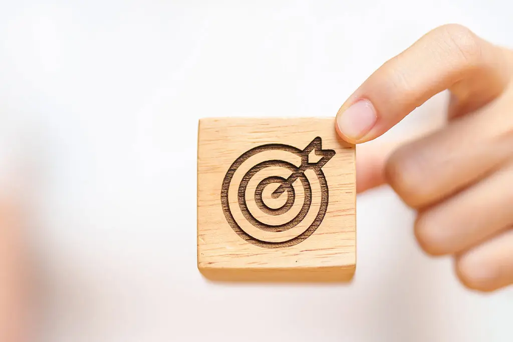 Hand holding a wooden block with a target symbol