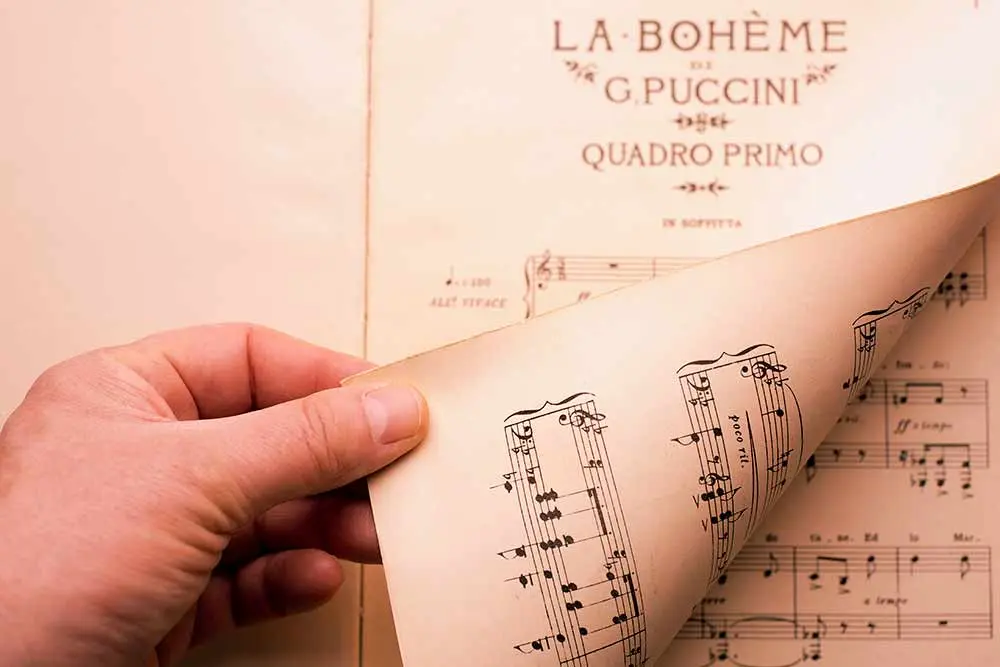 A man turning the pages of a Puccini score