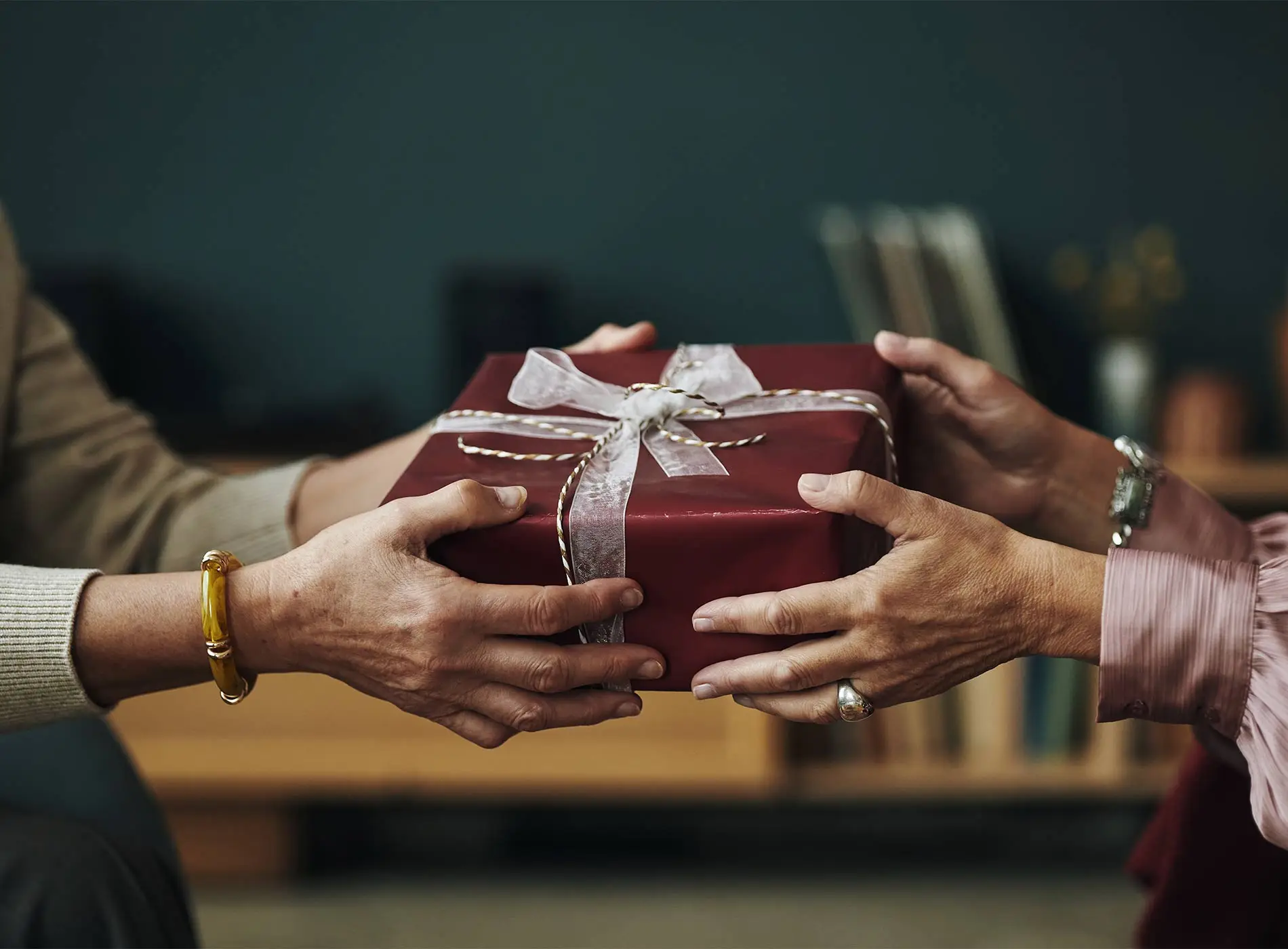 Two people exchanging a wrapped gift box
