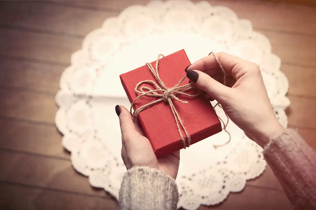 Hands holding a red gift box tied with string