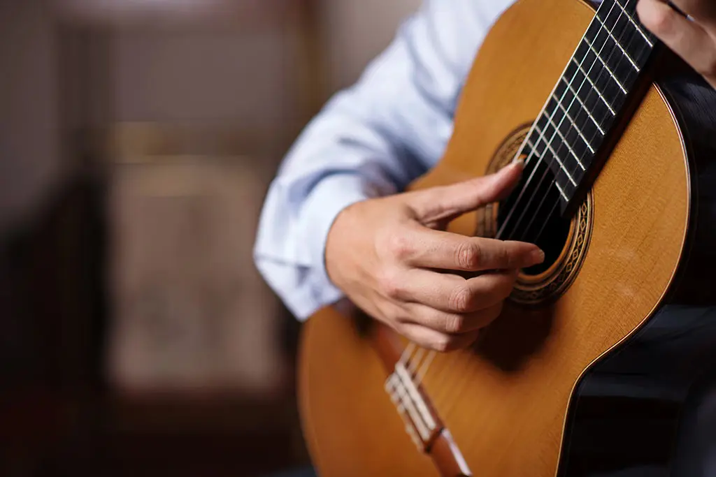 Hands playing a classical guitar close up