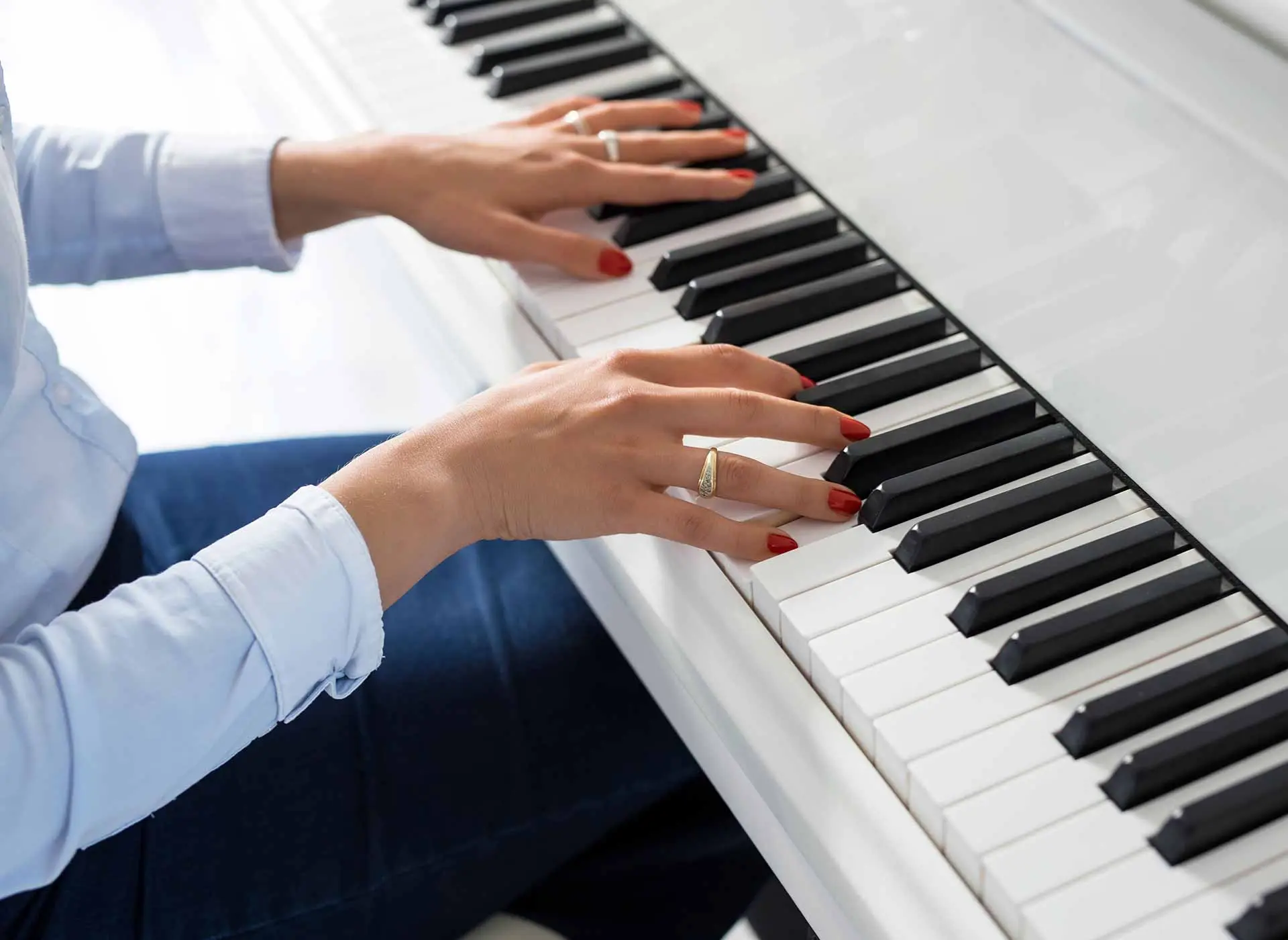 Hands playing a white piano keyboard