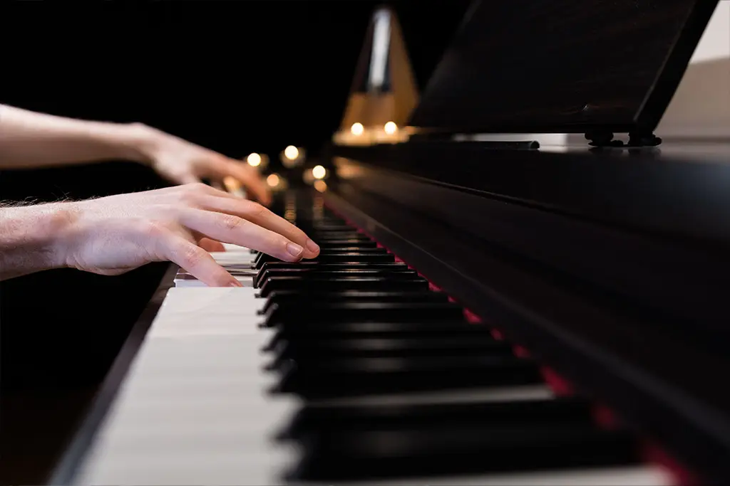Hands playing piano with metronome on the background