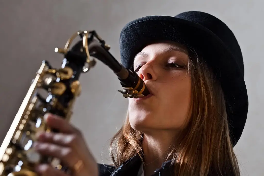 Lady wearing a hat playing saxophone
