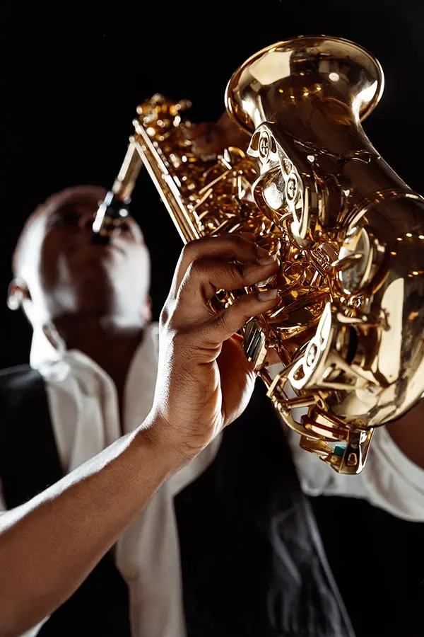 Low angle close-up of a man playing saxophone against black