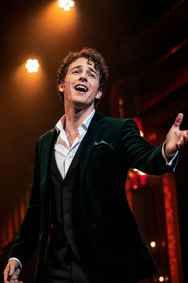 Male singer performing expressively under warm stage lights