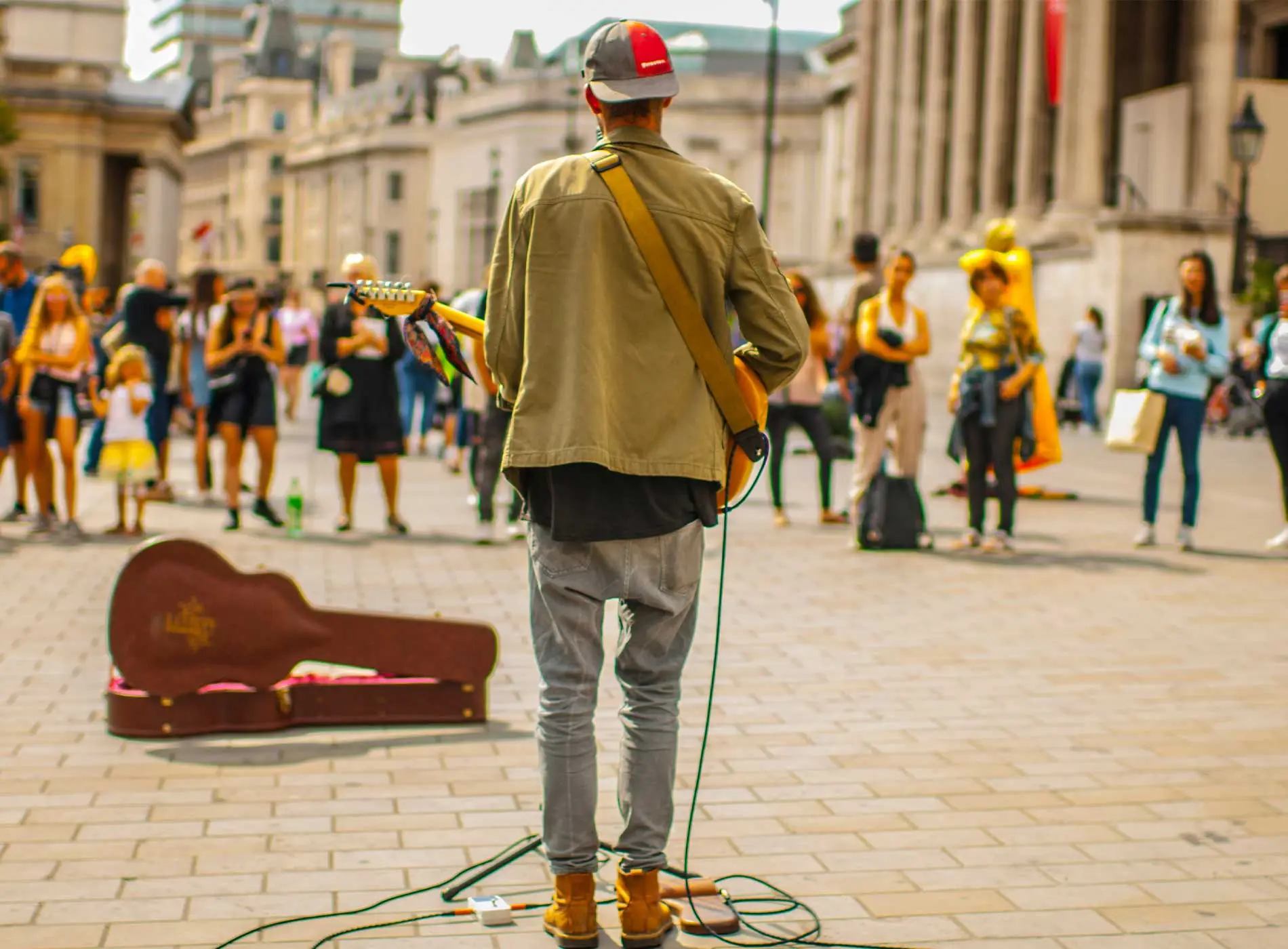 Man busking with an electric guitar on a busy street