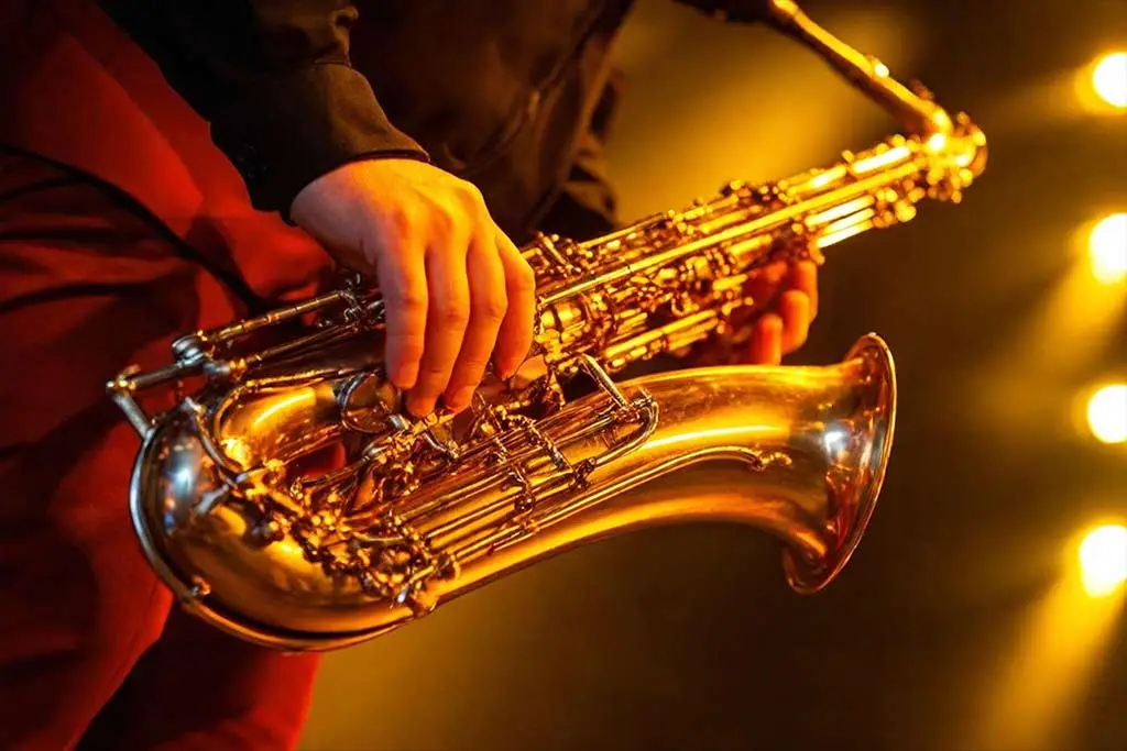 Man holding a saxophone with spotlight background