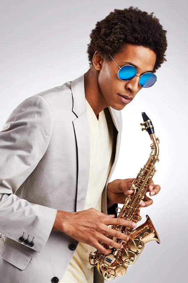 Man in blue sunglasses holding an alto saxophone close to camera