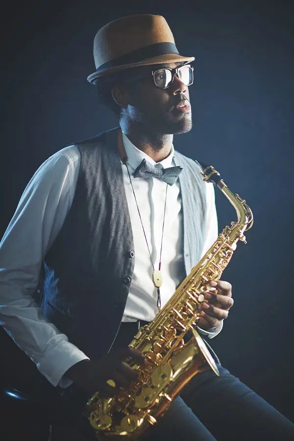 Man in a brown hat holding an alto saxophone