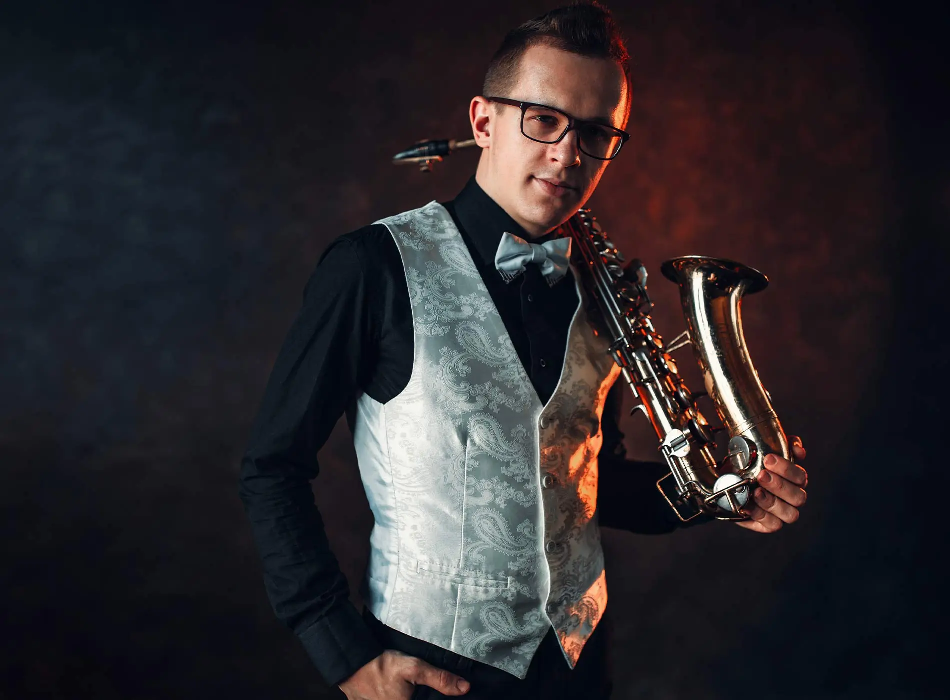 Man with glasses holding saxophone
