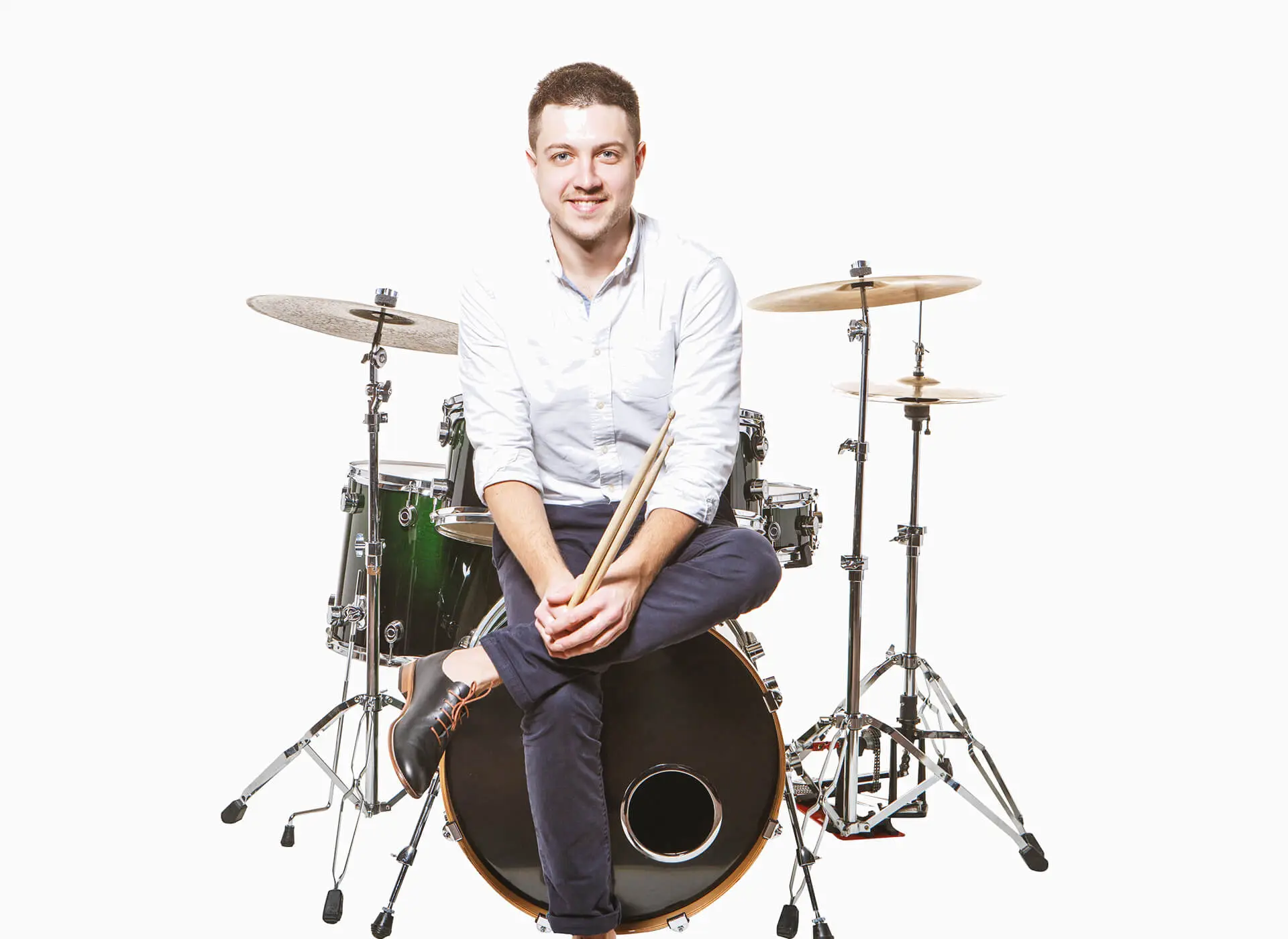 Man holding drumsticks while seated at a drum kit