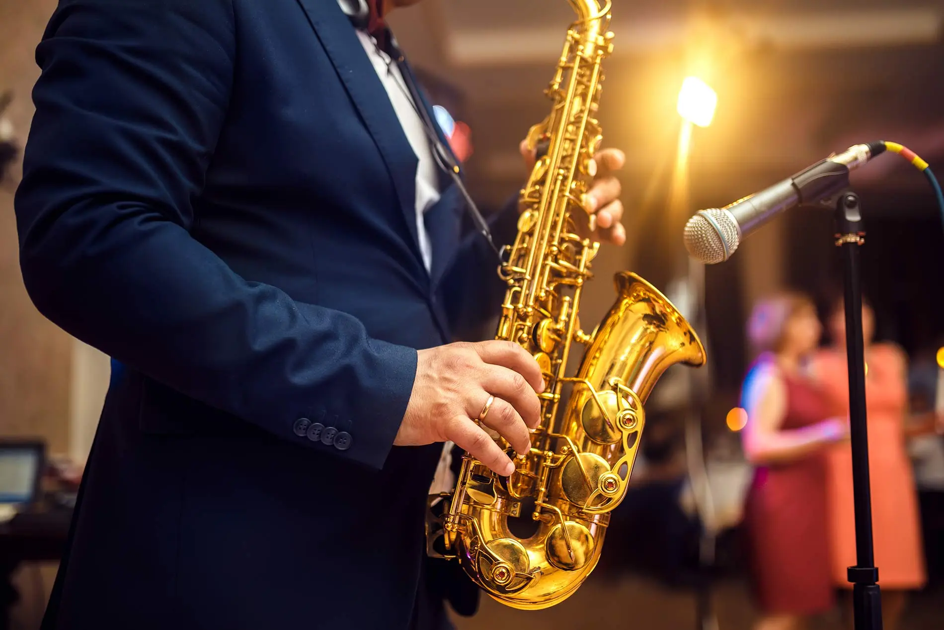 Man in navy blue suit holding saxophone