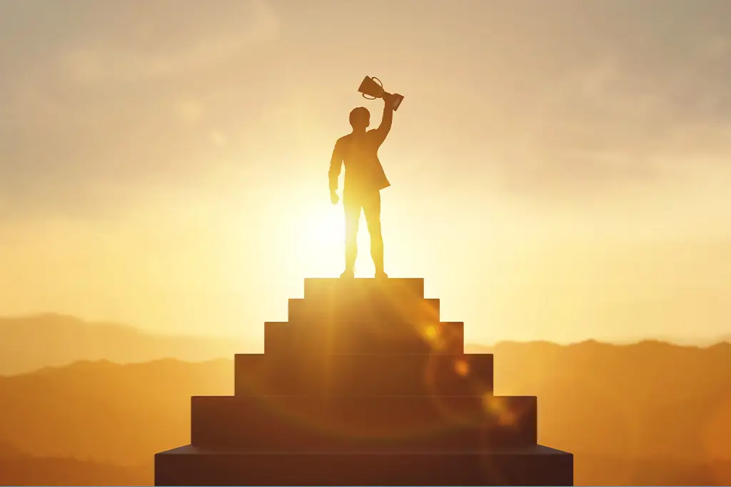 Man holding a trophy on steps at sunset