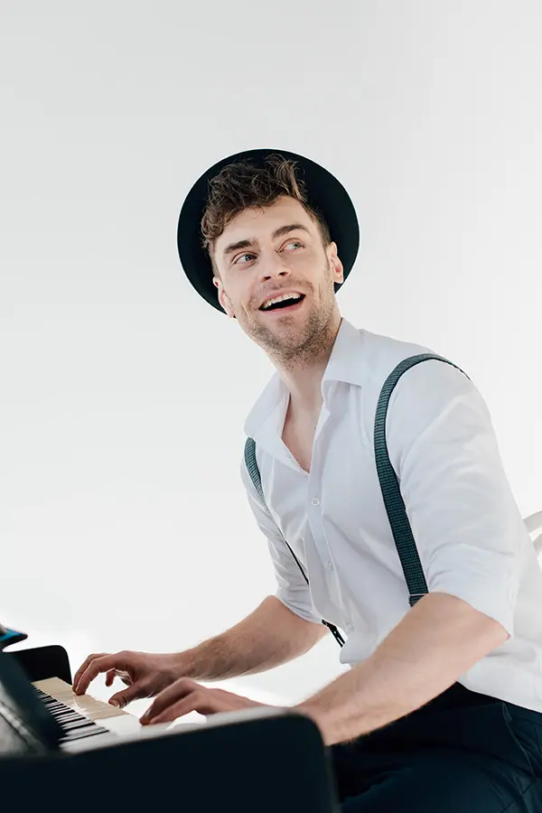 Man in a black hat and white shirt playing keyboard