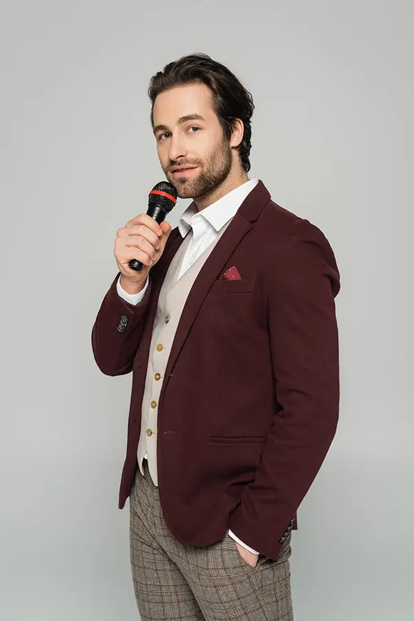 Man in a burgundy jacket holding a microphone