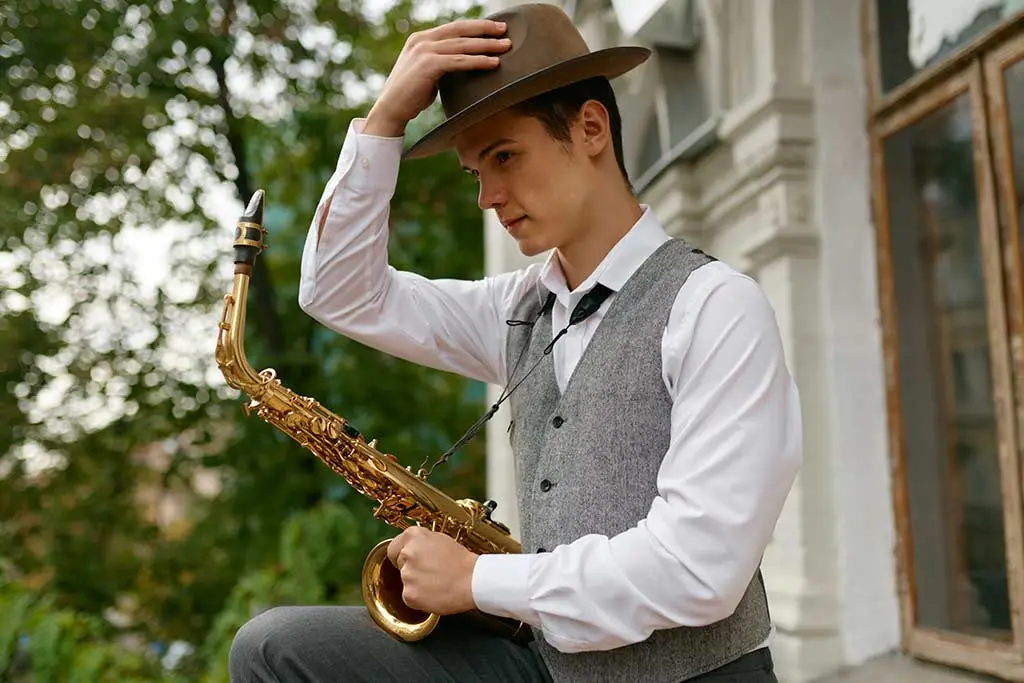 Young man in a hat holding an alto saxophone