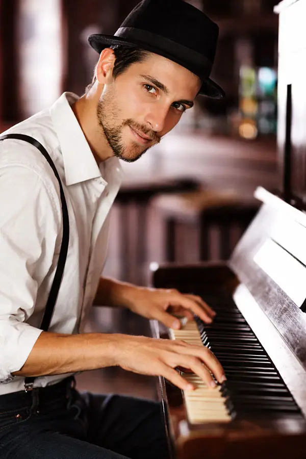 Man in a hat playing piano in a close-up view