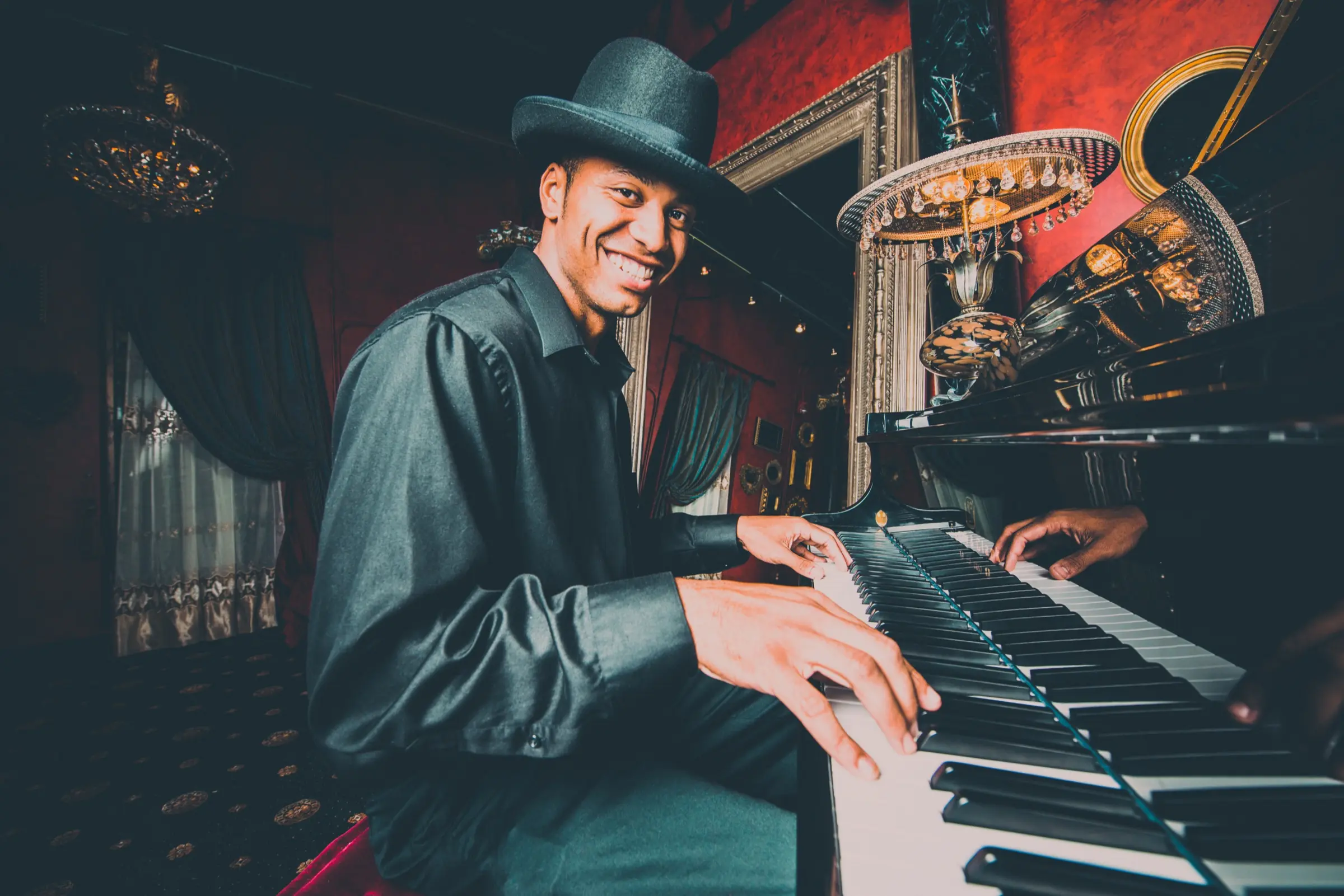 Smiling man in a hat playing the piano in an ornate bar.