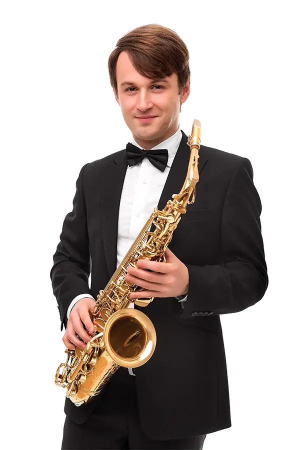 Man in suit smiling holding a saxophone