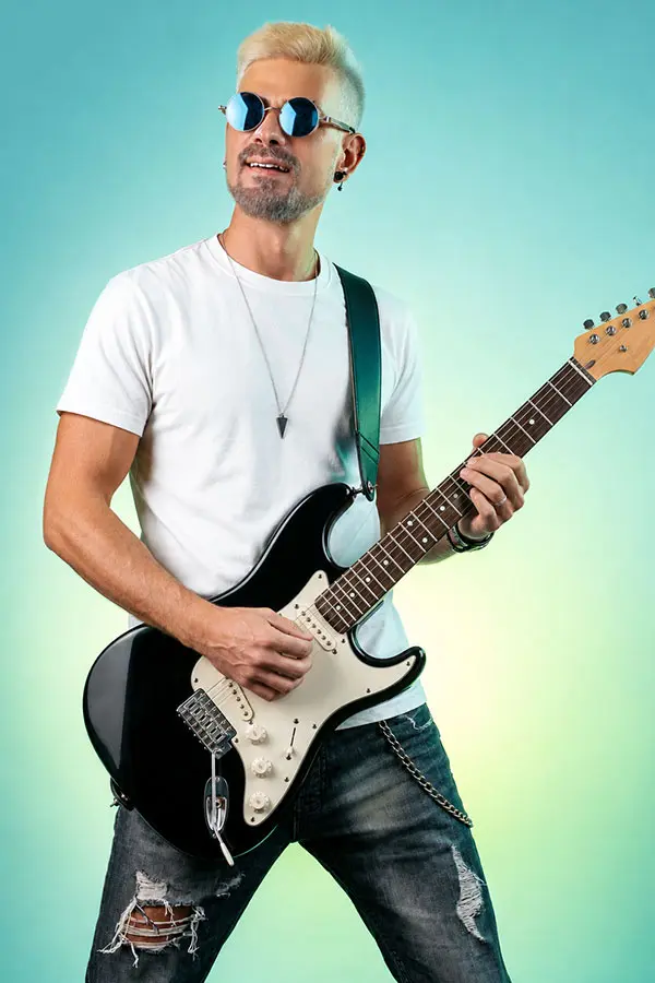 Man in sunglasses and a white shirt playing a black electric guitar