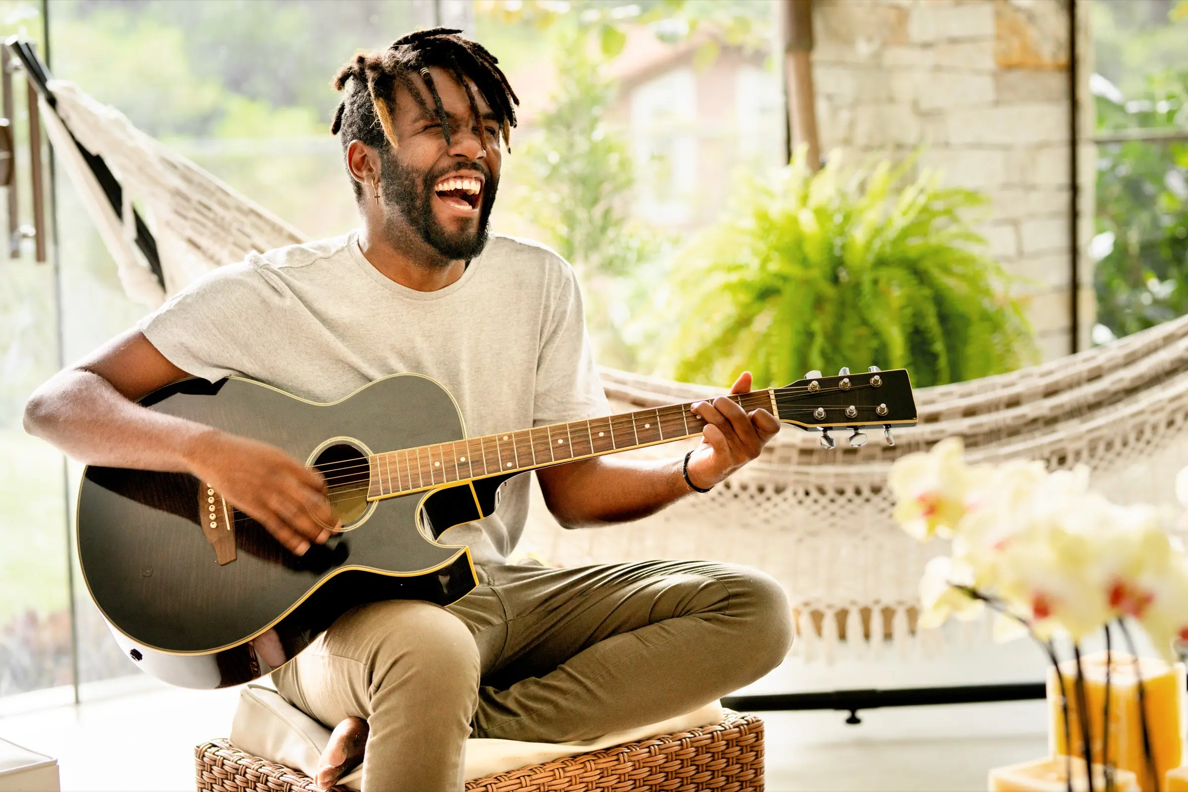 A man laughing as he plays an acoustic guitar at home