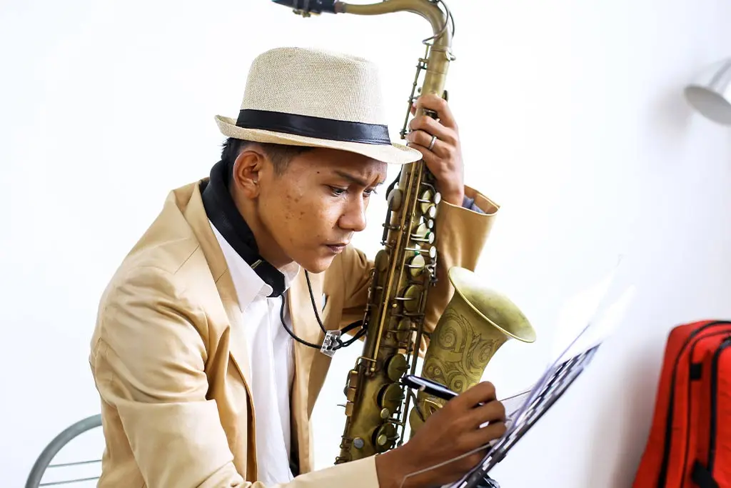 Man with a tenor saxophone marking sheet music