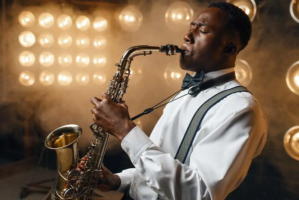 Man in a bow tie playing alto saxophone before bright lights