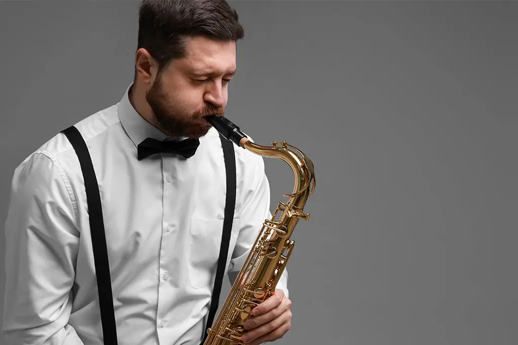 Man in braces and a bow tie playing alto saxophone