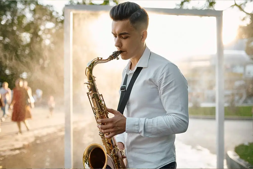 Man playing an alto saxophone in warm sunlight