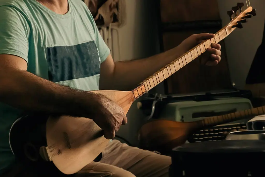 Man playing a baglama in a dim room