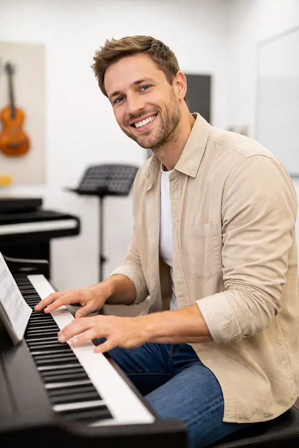 Smiling man playing a digital piano in a music room