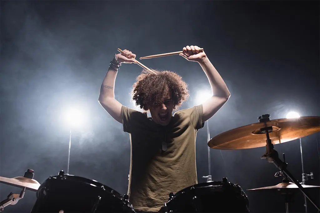 Man raising drumsticks over a drum kit on stage