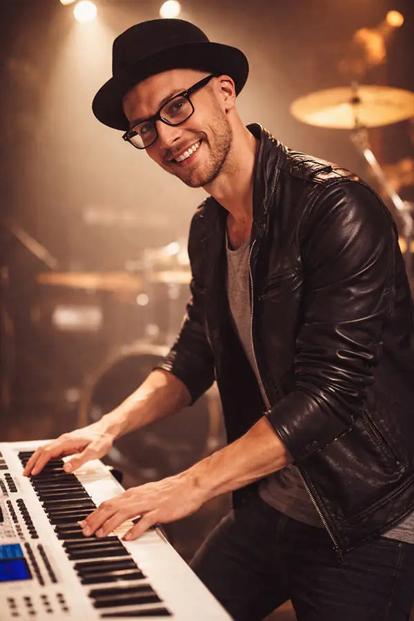 Man in a hat playing an electronic keyboard on stage