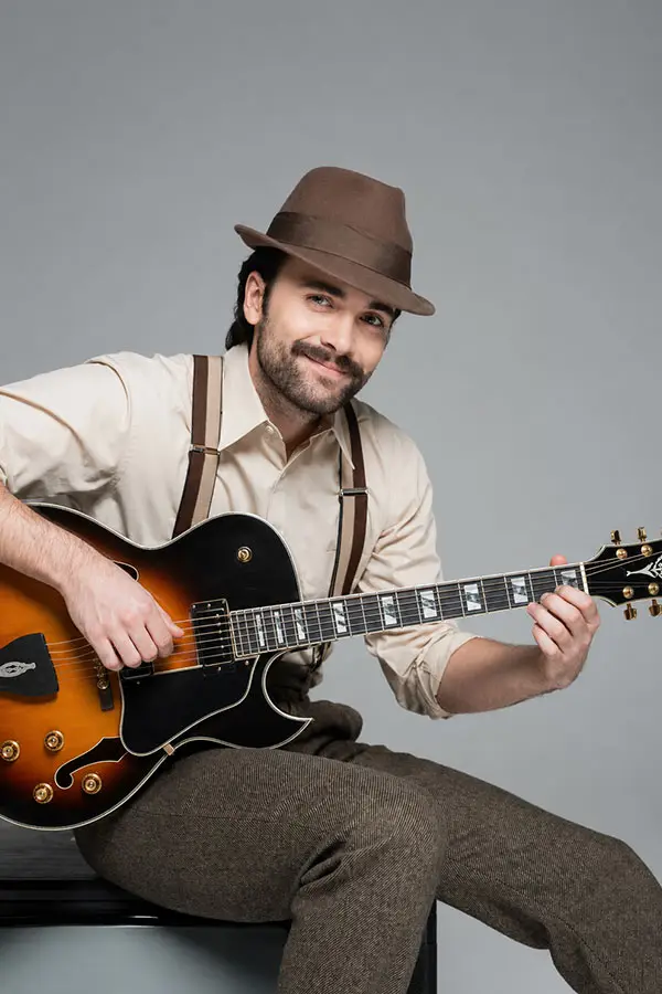 Man in a hat playing a hollow body electric guitar
